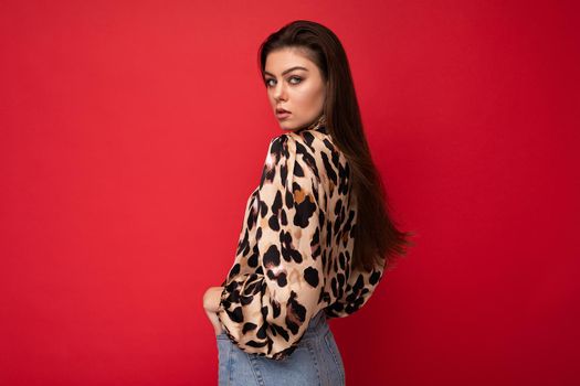 Close-up portrait of young nice-looking attractive lovely glamorous brunet woman wearing leopard blouse isolated on red color background with free space.