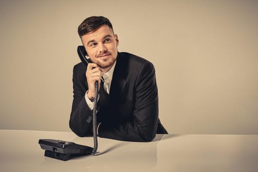 A young man in a black suit dials the phone number while sitting in the office. Manager talking on the phone