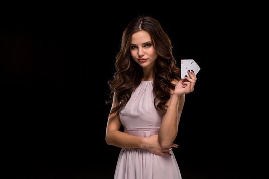 Attractive young woman in a sexy light dress holding the winning combination of poker cards. Two Aces. Studio shot on a black background. Casino