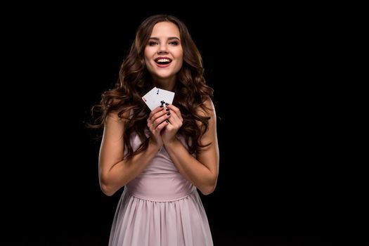 Sexy curly hair brunette posing with casino cards two aces in her hands, poker concept black background. Casino, poker, Roulette Blackjack Spin. Big win. winning combination emotions