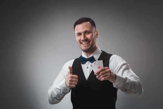 Handsome confident man holding cards looking at camera. Studio shot on gray background. Two Aces. Emotions happy win