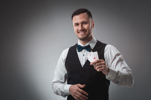 Handsome confident man holding cards looking at camera. Studio shot on gray background. Two Aces. Emotions happy win