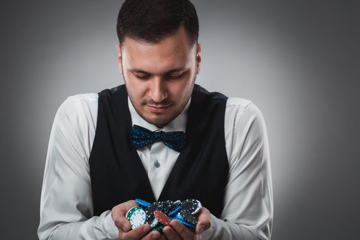 Young man in shirt and waistcoat shows his poker chips, studio shot. Poker. Emotions