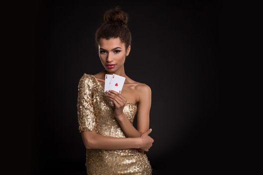 Woman winning - Young woman in a classy gold dress holding two aces, a poker of aces card combination. Studio shot on black background