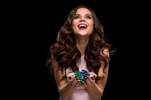 Female Poker player with paint black nails hold her poker chips to make a bet. Gambling and casino business concept. Studio shot on a black background. Casino