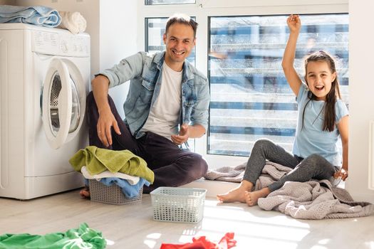 Happy Family loading clothes into washing machine in home