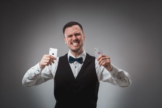 Young man in shirt and waistcoat shows his poker cards, studio shot. Poker. Emotions