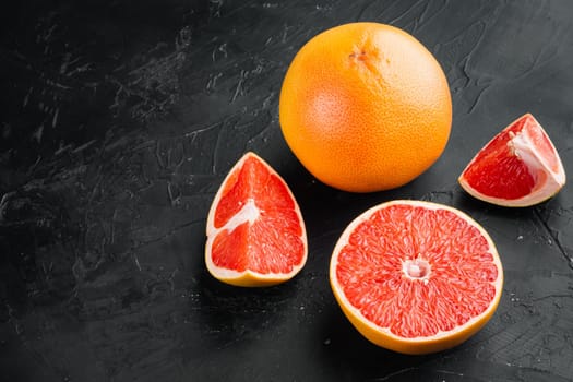 Ripe slice of pink grapefruit citrus fruit set, on black dark stone table background, with copy space for text