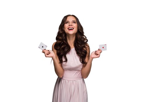 Beautiful confident woman in a sexy dress showing poker cards, looking up with copy place. Studio shot on white background. Casino