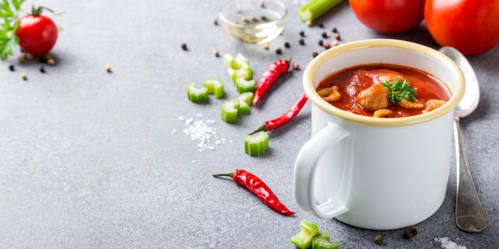 Delicious homemade tomatoes soup with meatballs in enamel mug. Healthy food concept with copy space.