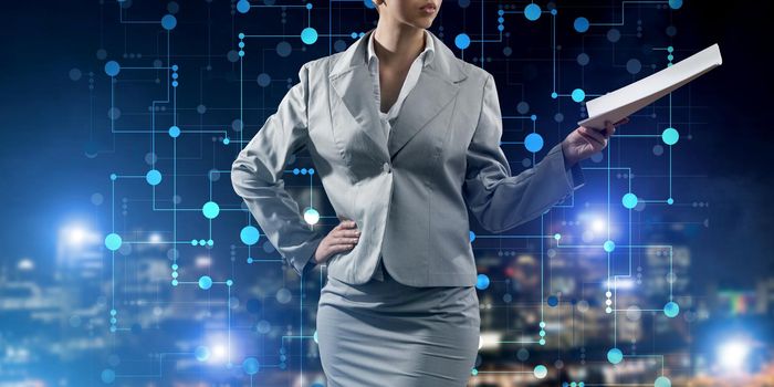 Businesswoman wearing modern suit and holding contract or report in her hand