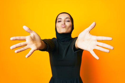 pretty woman in black hijab posing fashion hand gesture yellow background. High quality photo