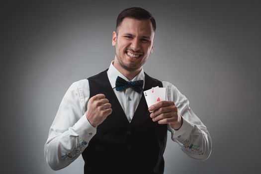 Handsome confident man holding cards looking at camera. Studio shot on gray background. Two Aces. Emotions happy win