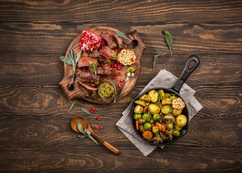 Overhead shot of meat steak with Fried potatoes with vegetables and herbs on wooden cutting board. Healthy holiday food concept with copy space.