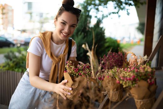 young beautiful brunette woman enjoying flowers in pots on the porch of a flower shop.