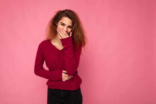 Photo of young happy positive pretty nice brunette wavy woman with sincere emotions wearing casual pink sweater isolated over pink background with empty space and laughing.