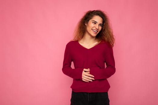 Photo of young happy positive pretty nice brunette wavy woman with sincere emotions wearing casual pink sweater isolated over pink background with empty space and having fun.