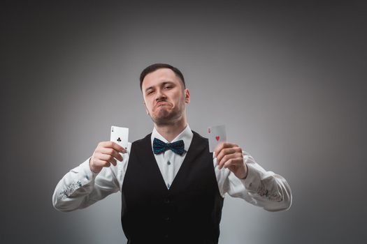 Young man in shirt and waistcoat shows his poker cards, studio shot. Poker. Emotions