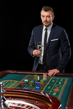 man in a suit playing roulette. addiction to gambling. In the hands of a glass