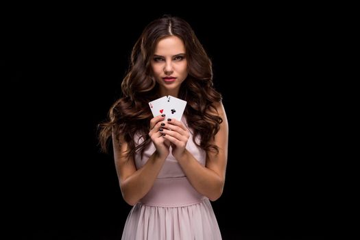 Attractive young woman in a sexy light dress holding the winning combination of poker cards. Two Aces. Studio shot on a black background. Casino