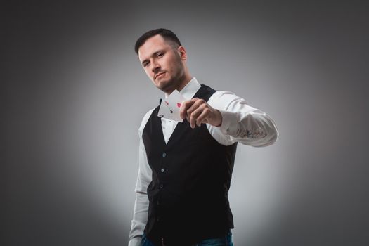 Handsome poker player with two aces in his hands. A man in the studio on a black-and-gray background