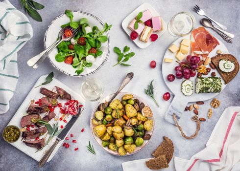 Flat lay of delicious dinner table with roasted meat steak, appetizers and desserts. Top view. Healthy food concept.