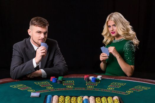 couple playing poker at the table. The blonde girl and a guy in a suit.