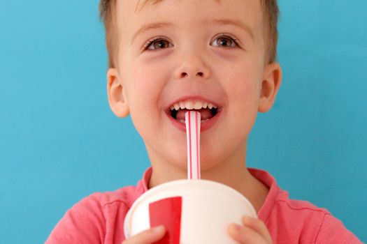 Cute little baby boy drinking milkshake blue background