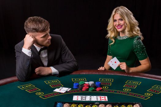 couple playing poker at the green table. The blonde girl and a guy in a suit. happy win, two aces