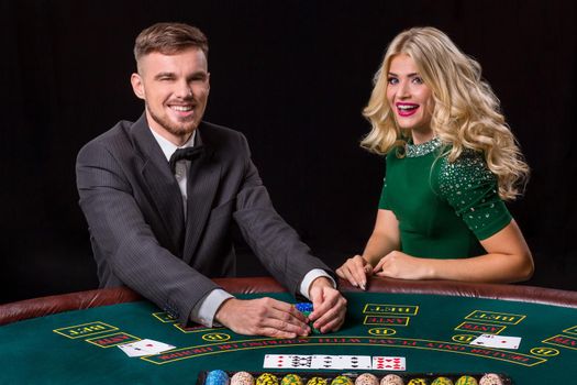 couple playing poker at the green table. The blonde girl and a guy in a suit. happy win