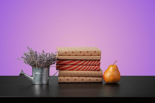 Education concept with stack of books on a table against colored background, front view