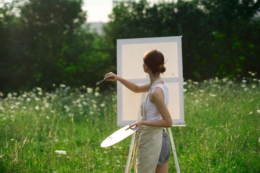 woman artist outdoors with palette of paints paints a picture. High quality photo