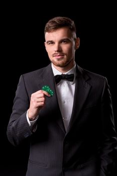 man in a suit posing with chips for gambling on black background
