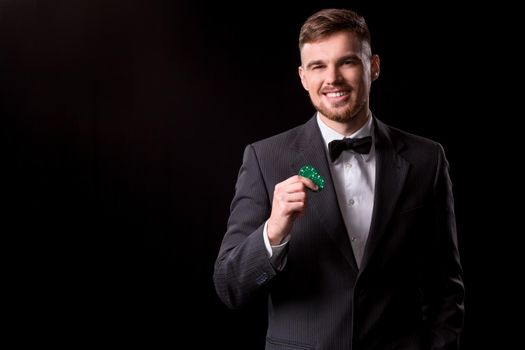 man in a suit posing with chips for gambling on black background