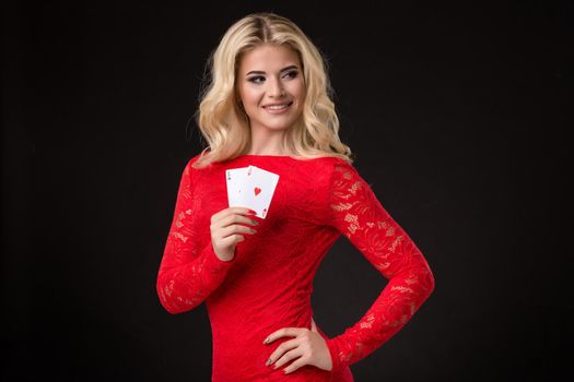 Young beautiful blond woman in a red dress with playing cards over black. Poker