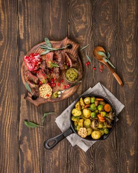 Meat steak with fried potatoes with vegetables and herbs on wooden cutting board. Healthy holiday food concept with copy space. Top view.