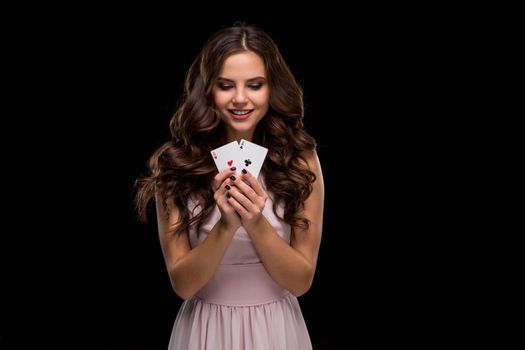 Attractive young woman in a sexy light dress holding the winning combination of poker cards. Two Aces. Studio shot on a black background. Casino