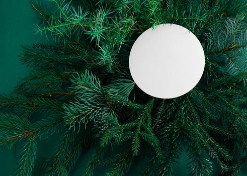 Christmas green background. Pine branches, needles and Christmas trees. View from above. Round frame with place for text. Christmas nature background. December mood concept. Copy space.