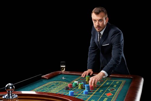 man in a suit playing roulette. addiction to gambling. In the hands of a glass. He bets chips