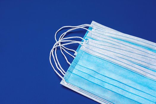 Medical face mask on blue background. Coronavirus covid-19 prevention concept
