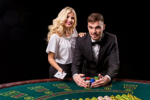 couple playing poker at the table. The blonde girl and a guy in a suit. happy win