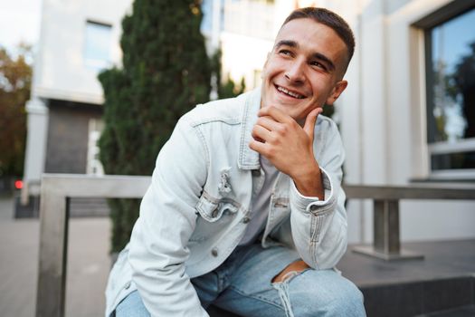 Young casual man sitting on stairs alone on city street