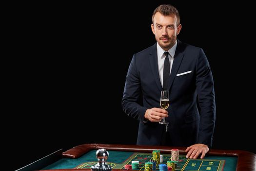 man in a suit playing roulette. addiction to gambling. In the hands of a glass