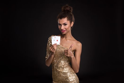 Pretty african girl shows two aces in casino poker and win Young woman in studio on black background