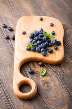 Fresh blueberries on cutting board on old wooden background. Healthy eating and nutrition concept with copy space.