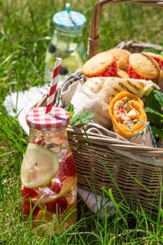 Picnic basket with food on green sunny lawn. Healthy eating.