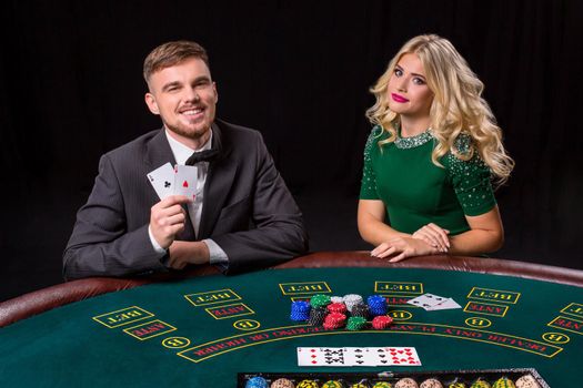 couple playing poker at the green table. The blonde girl and a guy in a suit. happy win, two aces