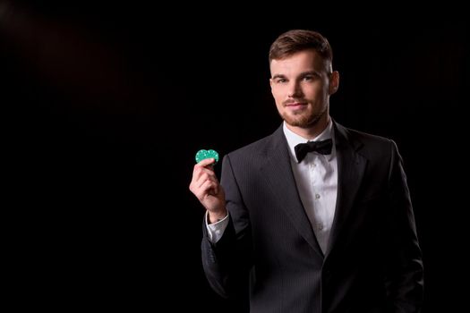 man in a suit posing with chips for gambling on black background