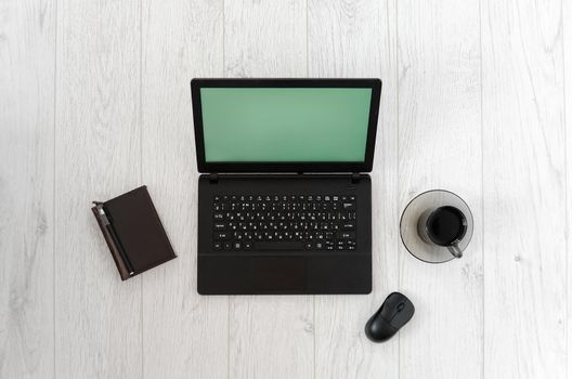 Laptop, computer mouse, cup of coffee and notebook on a wooden table. Top view