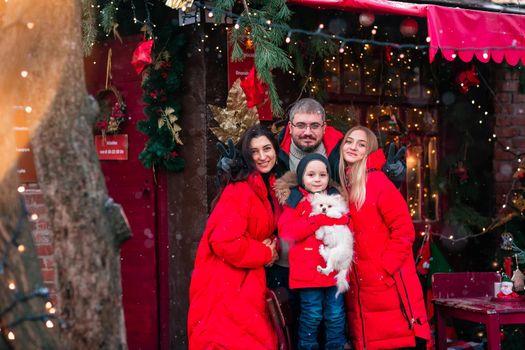 Happy family on the porch of the Christmas decorated house, snowing outdoor. Happy New Year and Merry Christmas. Magic winter